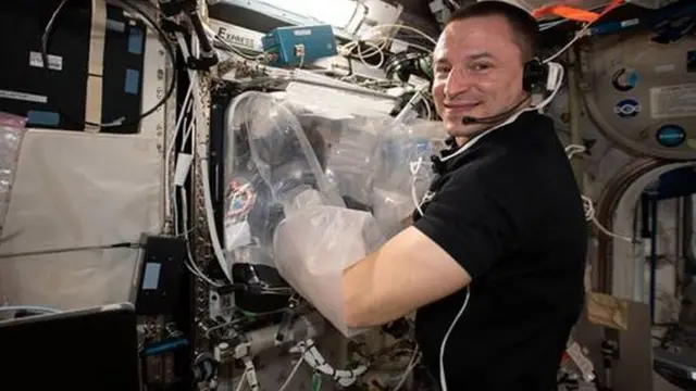 O astronauta Morgan faz experimentos e olha para a câmera sorrindo