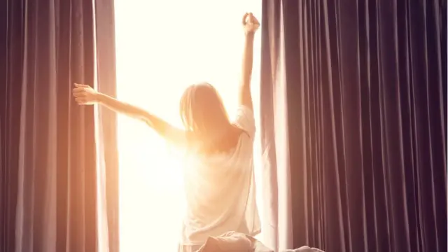 Mujer abriendo las cortinas