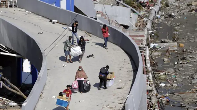 People carry goods looted from a tsunami devastated shopping mall in Palu, Central Sulawesi, Indonesia, 30 September 2018.