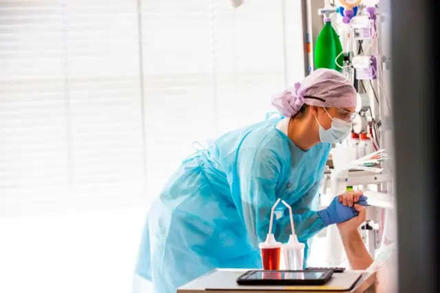 Una mujer sostiene la mano de un paciente en un hospital de Dinamarca.