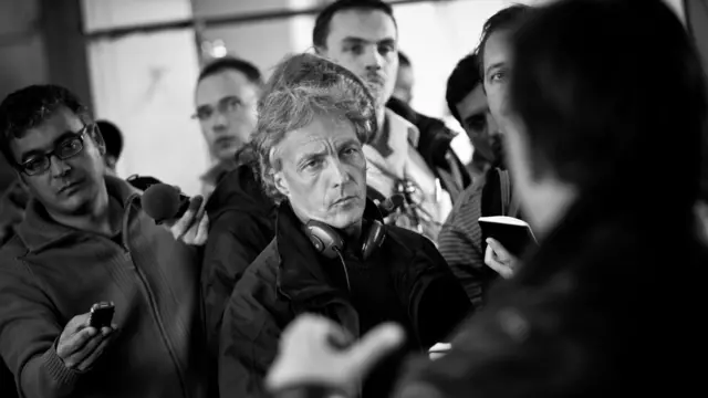 Újságírók láthatók egy fekete-fehér képen, középen Nick Thorpe, a BBC budapesti újságírója. A fotón csak hátulról látható Orbán Viktort, akkori magyar miniszterelnököt kérdezik a 2010. október 4-i ajkai vörösiszap-katasztrófa után.