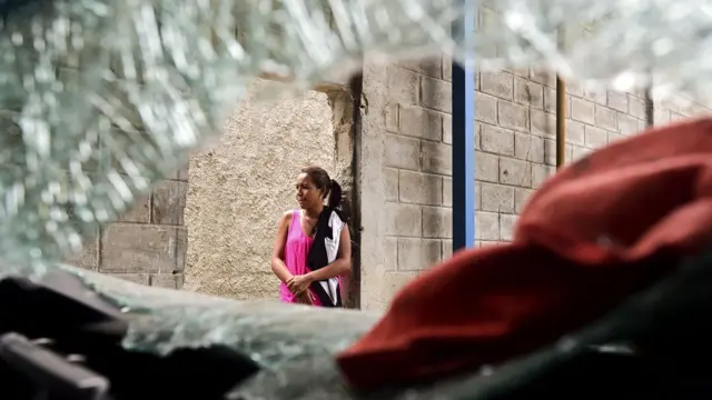 Una mujer desde un comercio saqueado.