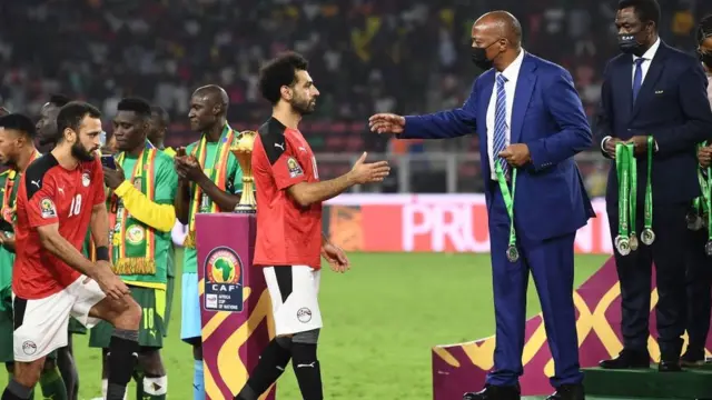 Le président de la Confédération africaine de football Patrice Motsepe (2R) remet une médaille à l'attaquant égyptien Mohamed Salah (C) après le match de la finale de la Coupe d'Afrique des Nations (CAN) 2021.