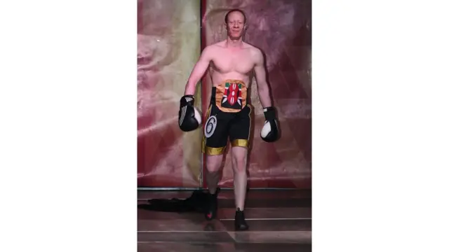 Miraba minne! John Ngatia, ambaye pia huwa anasakata densi, avalia sare ya mapigano ya ndondi katika maonyesho hayo, jijini Nairobi Kenya tarehe 21 Oktoba 2016