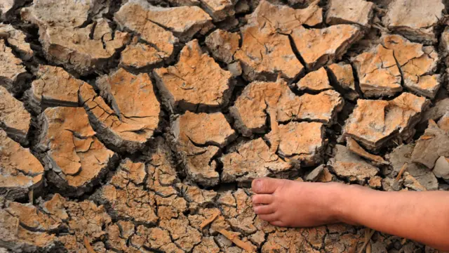 Pie de un niño muy pequeño sobre tierra quebrada por la seca