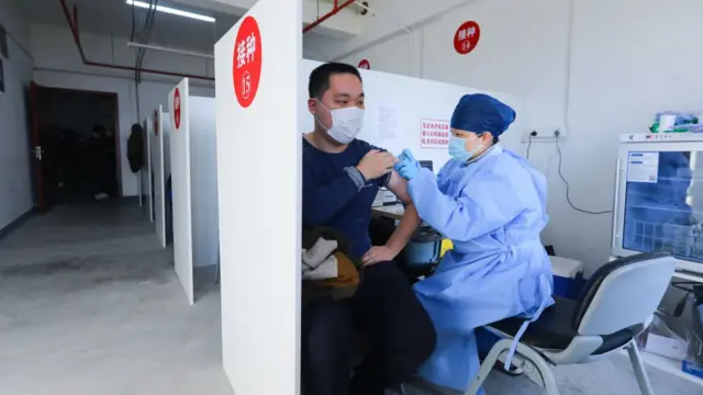 साङ्घाइ चीनमा एकजना स्थानीय बासिन्दा कोभिड १९ को खोप लिँदै