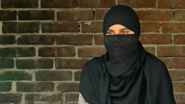 Asma başını və üzünü örtərək tərəddüd içində danışır