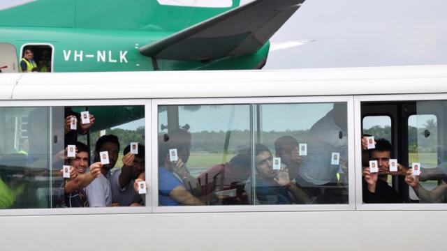 身分証明書を掲げるパプアニューギニアのマヌス島に到着した難民申請者たち