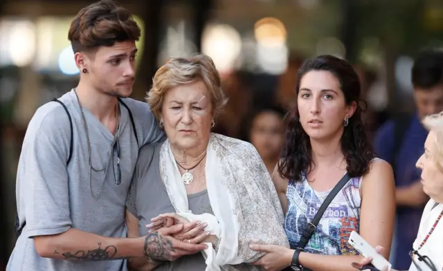 Mujer herida ayudada por otras personas