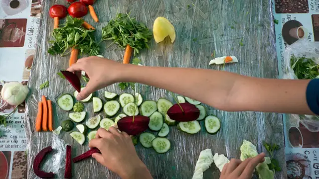 Manos de un niño acomodando verduras sobre una mesa.