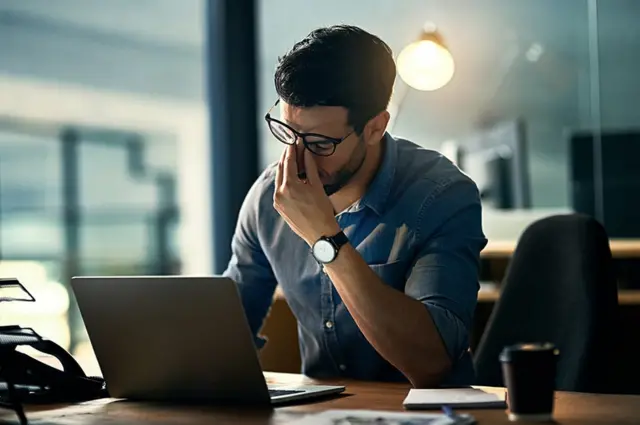 Homem exaustojogo esportefrente a um laptop