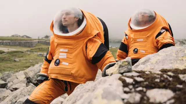 Estudantes com trajes laranja de astronauta.