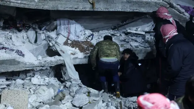 سكان يبحثون عن ضحايا وناجين وسط أنقاض مبنى انهار في قرية عزمارين، بالقرب من الحدود التركية شمالي محافظة إدلب السورية ، 6 فبراير/شباط 2023