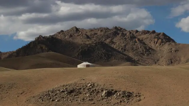 أرض مقفرة في منطقة جبلية تتوسطها خيمة