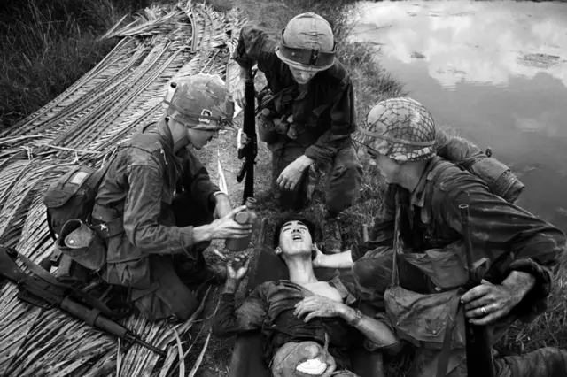 American soldiers treat an injured Vietnamese soldier