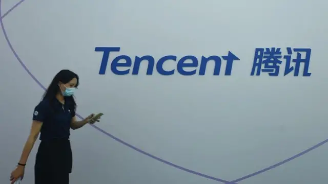 Uma mulher andandorollover novibet como funcionafrente a um logo da Tencent