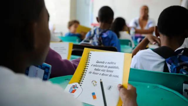 Crianças olhando material escolar em sala de aula