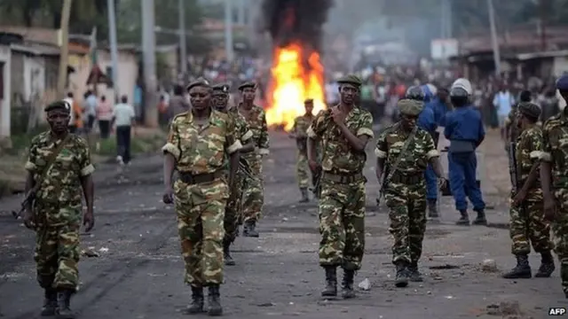 Burundian soldiers walk near a burning barricade erected by protesters as people demonstrate against the president's bid for a third term in power in Musaga, in the outskirts of Bujumbura, on April 27, 2015