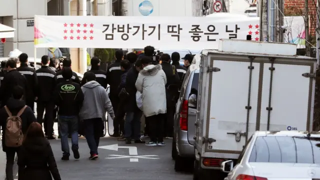 22일 이 전 대통령의 서울 논현동 사저 근처에서 시민들이 현수막을 들고 있다