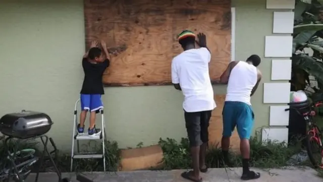 Warga menutup jendela di Port Salerno, Florida, bersiap menghadapi terjangan topan.