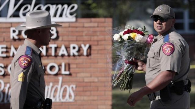 Polisi membawa karangan bunga di sekolah dasar Robb di Uvalde, Texas.