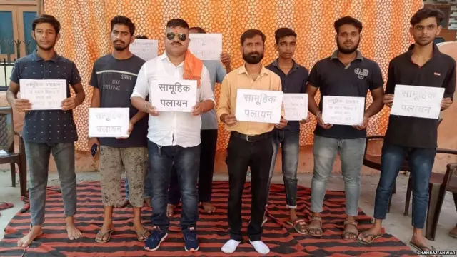 सामूहिक पलायन का पोस्टर लिए लोग