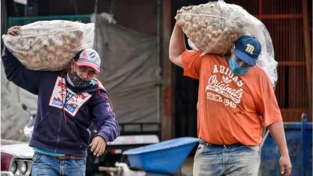 dois homensapostar quina onlinemáscaras carregando sacosapostar quina onlinealimentos na rua