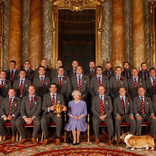 A rainha, acompanhada do corgi Berry, com o time de rugby da Inglaterra, em uma recepção no Palácio de Buckingham para comemorar a conquista da Copa do Mundo de Rugby