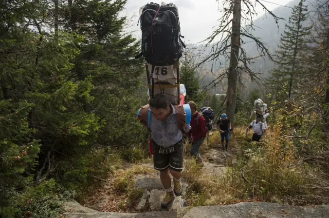 Sherpa subindo uma montanha carregando várias bolsas