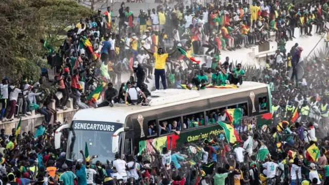 Des supporters applaudissent Aliou Cissé, l'entraîneur de l'équipe de football du Sénégal, qui soulève le trophée à Dakar, le 7 février 2022, après avoir remporté la Coupe d'Afrique des Nations.