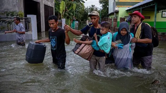Warga meninggalkan rumah mereka yang terendam banjir akibat jebolnya tanggul Sungai Jratun-Wulan, di Desa Undaan Kidul, Kecamatan Karanganyar, Kabupaten Demak, Jawa Tengah, Kamis (8/2/2024).