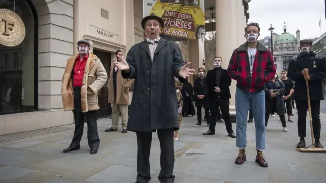 Пол Уайтхаус, играющий в мюзикле "Дуракам везет" одну из главных ролей, с другими актерами во время 15-минутной акции у здания театра