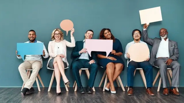 Shot portrait of a diverse group of people holding up speech bubbles while they sit in line