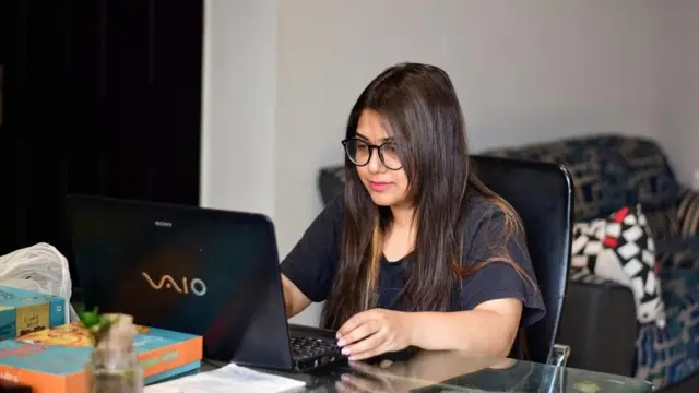 فتاة تجلس أمام كمبيوتر