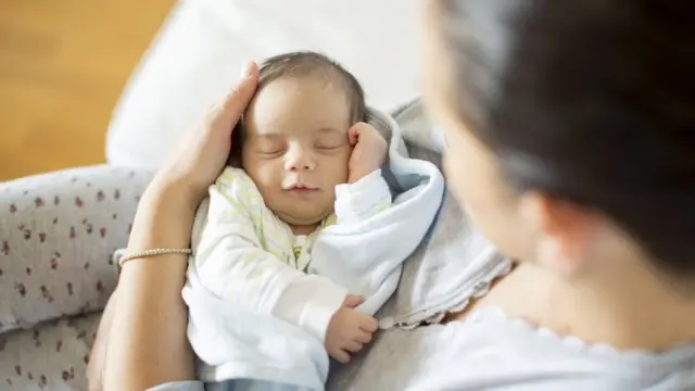 Bebê dormindo no colo da mãe