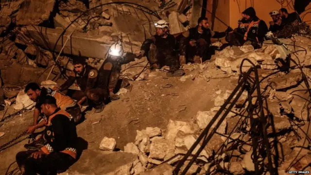 Syrian Civil Defence volunteers create a human chain as they search for survivors amid the rubble following an explosion in the rebel-held city of Idlib on late April 9, 2018