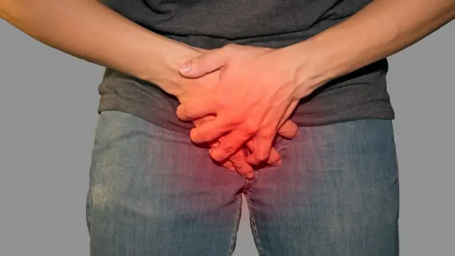 Hombre tocándose lo genitales.