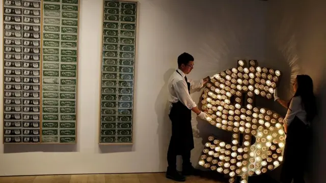 Знак доллара до сих пор пользуется популярностью у художников (Тим Ноубл и Сью Уэбстер устанавливают свою сияющую инсталяцию рядом с работами Энди Уорхола)