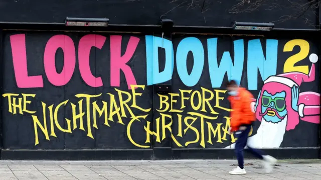 رجل يمر بجوار لوحة جدارية كتب عليها: "الإغلاق رقم 2 الكابوس قبل الكريسماس.