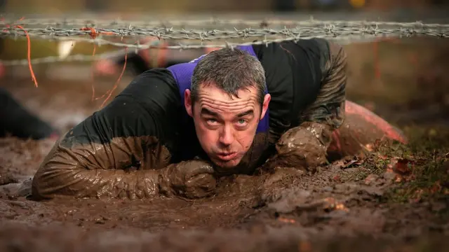Persona pasando por debajo de alambres de púas.