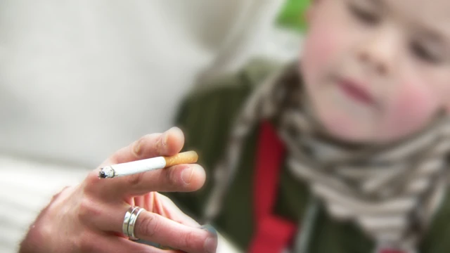Niño junto a un adulto fumando