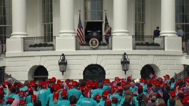 People in blue T-shirts and red MAGA caps gather outside the White House (10 Oct)