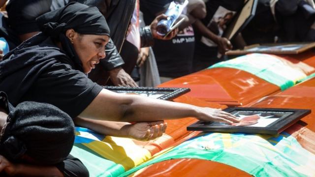 A mourner of victims of the Ethiopian Airlines crash touches a portrait on a coffin during the mass funeral at Holy Trinity Cathedral in Addis Ababa, on 17 March