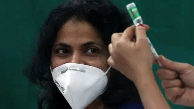 A healthcare worker looks on as a nurse prepares a dose of the AstraZeneca"s COVISHIELD vaccine, during the coronavirus disease (COVID-19) vaccination campaign, at a medical centre in Mumbai, India, January 16, 2021.