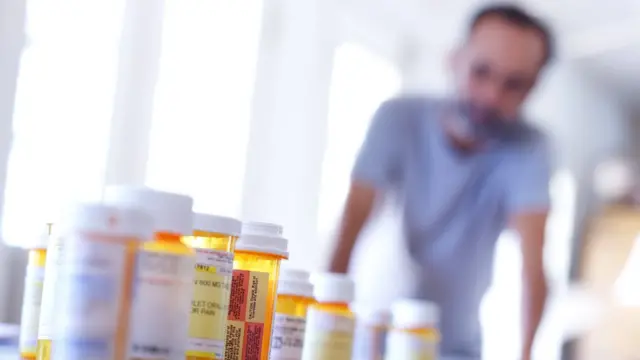 Un hombre mira a tubos con pastillas.