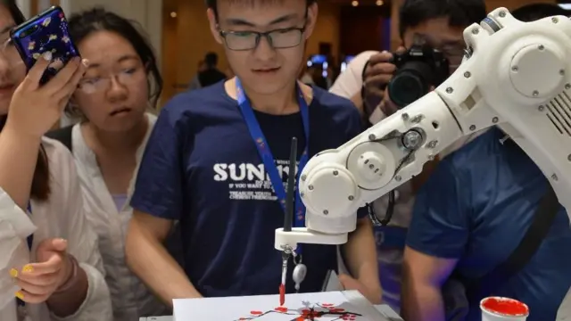 Jovens observam robô pintando durante a abertura do 3º World Intelligence Congressreal bet paga mesmoTianjin, na China.