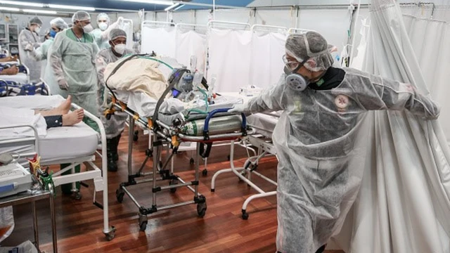 Profissionais da saúde puxam uma maca num hospital