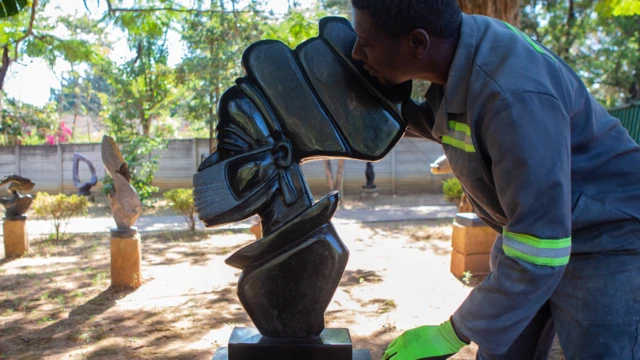 Wani mai sassaka gumaka dan Zimbabwe, Zimbabwea yana nuna daya daga cikin ayyukansa da ke nuna sassakar mace sanye da takunkumi a birnin Harare ranar Juma'a.