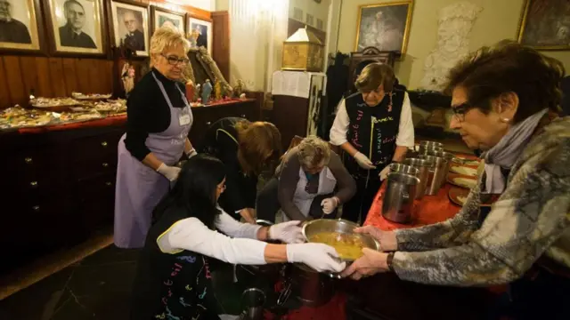 Mujeres preparan comida para los menos favorecidos en ocasión de Navidad.