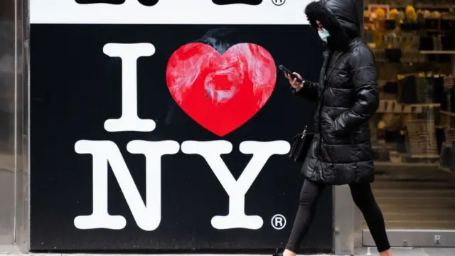 Mulher passando por uma placa "Eu amo Nova York"